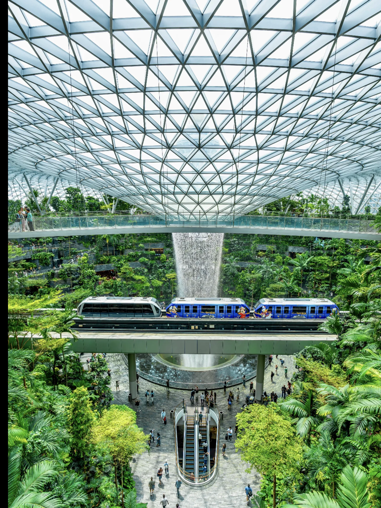 Jewel Changi Airport interior with the Rain Vortex, greenery and a train passing through